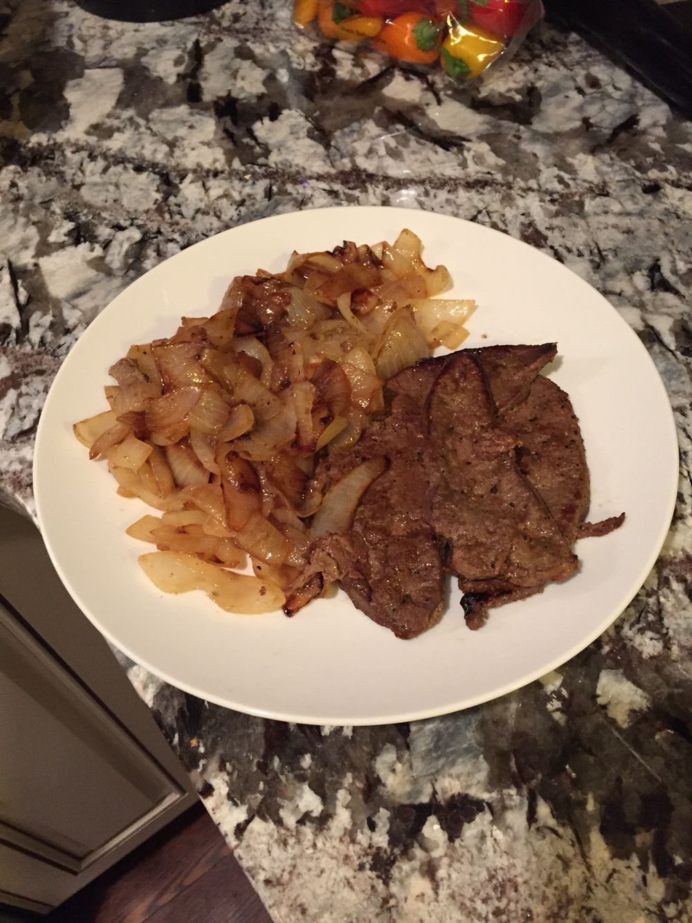 Cooked beef liver and sautéed onions served on a white plate.