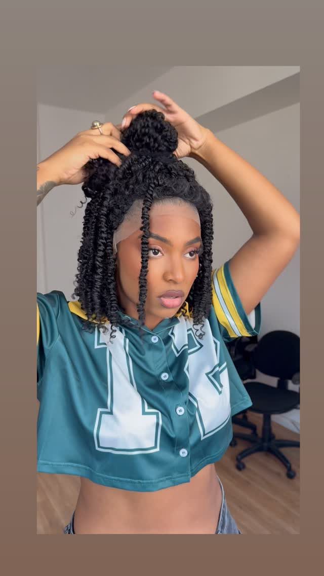 Woman with braided half-up afro curls wearing a green athletic jersey.