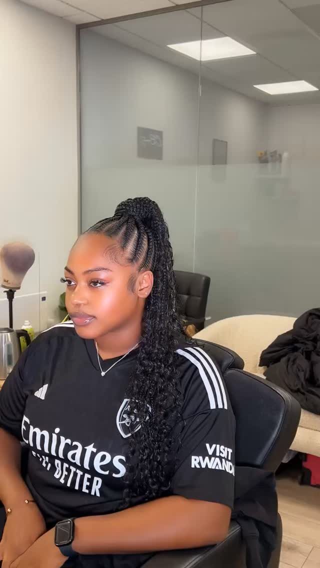 Woman with dark hair styled in a high braided ponytail wearing a black jersey.
