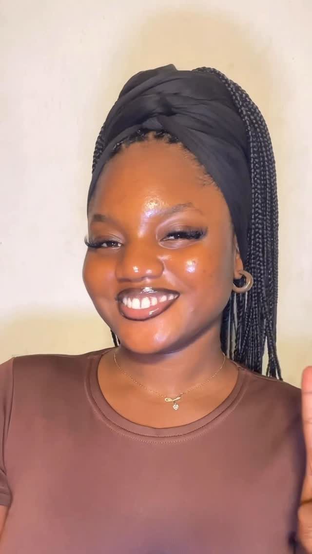 Woman with long black box braids wearing a black wrapped headscarf and brown shirt.