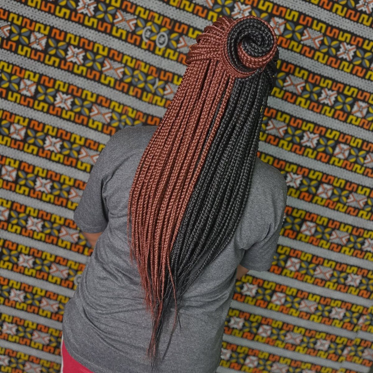 Two-toned reddish-brown and black chunky box braids styled into a large circular roll.