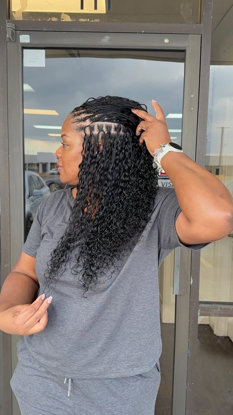 Woman with long curly black crochet braids and scalp braids wearing grey clothing.