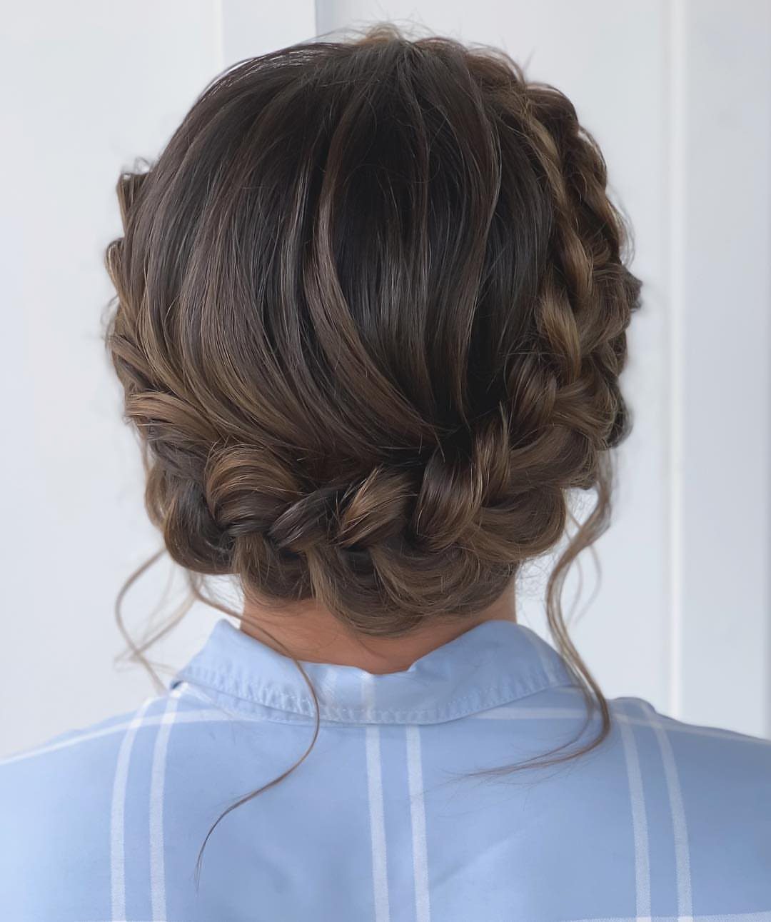 Brown hair styled in a crown braid and low braided bun from behind.