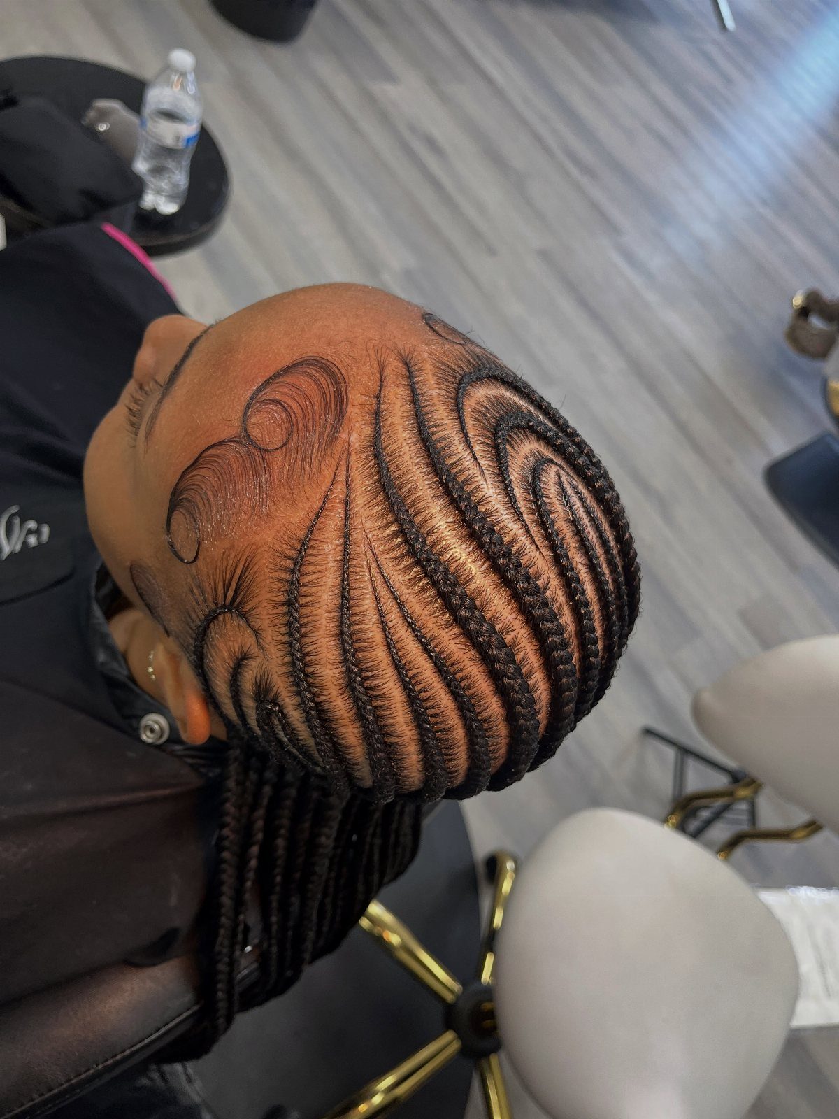 Intricate curved cornrow braids styled to the scalp in a swirling artistic pattern