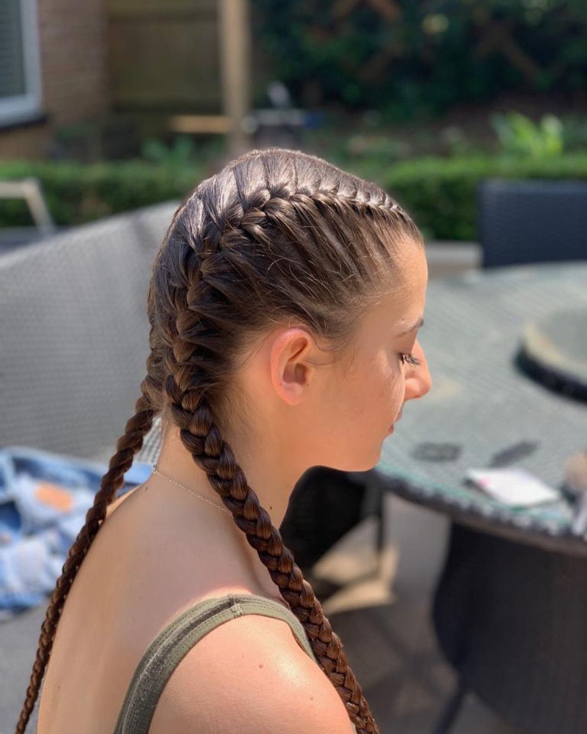 Woman with brown hair styled in two Dutch braids extending into pigtails.