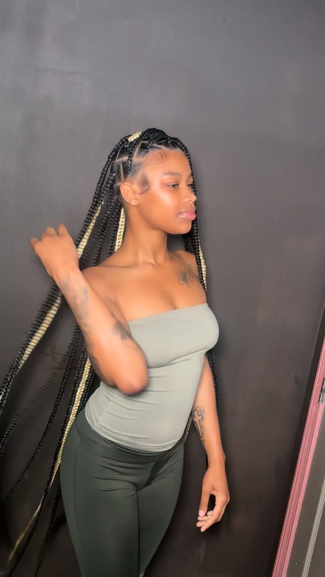 Woman with long black and blonde knotless braids wearing a green tube top.