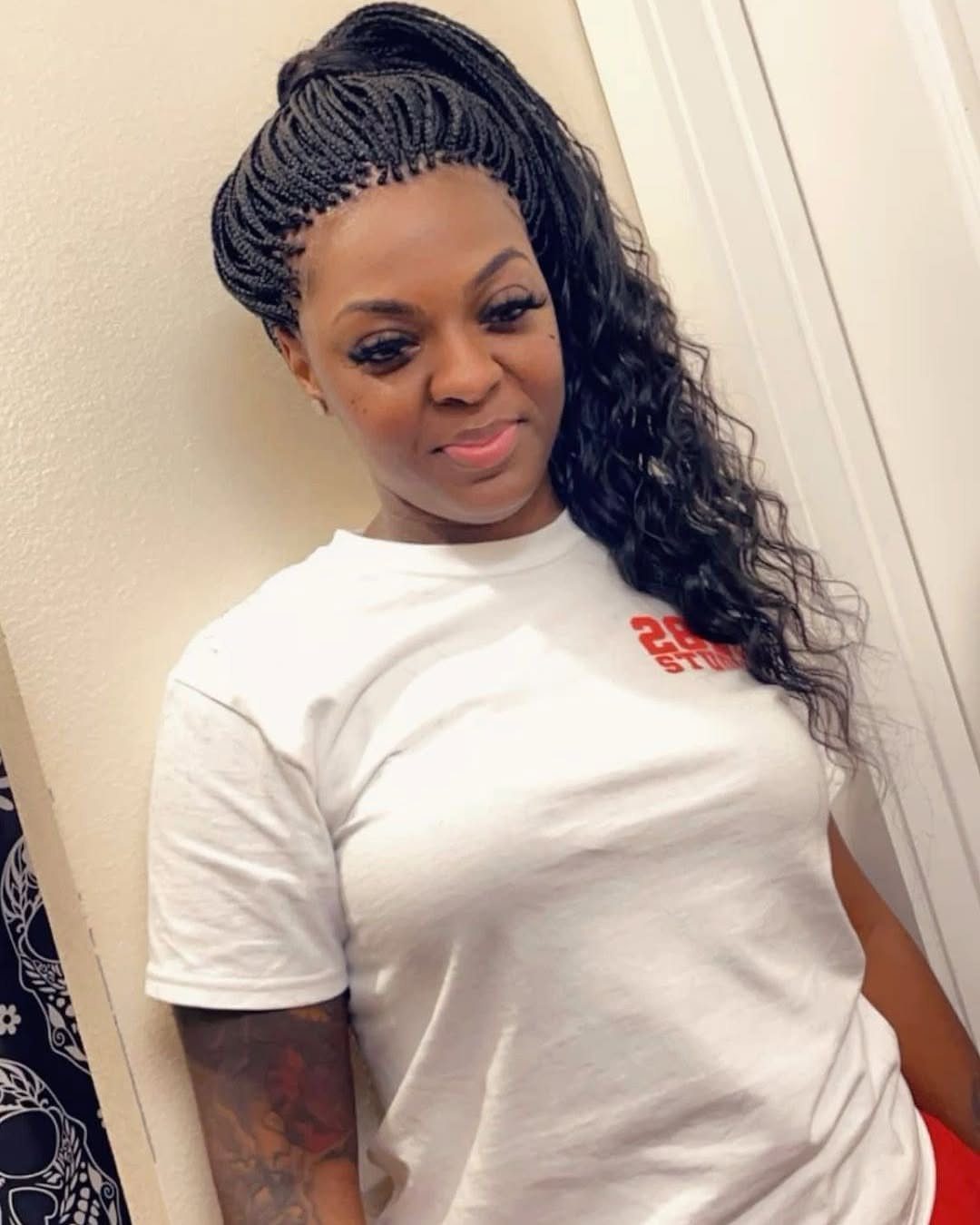 Woman with black hair styled in scalp braids and a long wavy ponytail.