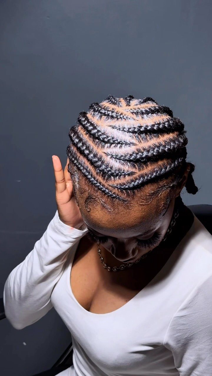 Woman with silver-highlighted stitch braids styled in crisp, horizontal lines across her scalp.