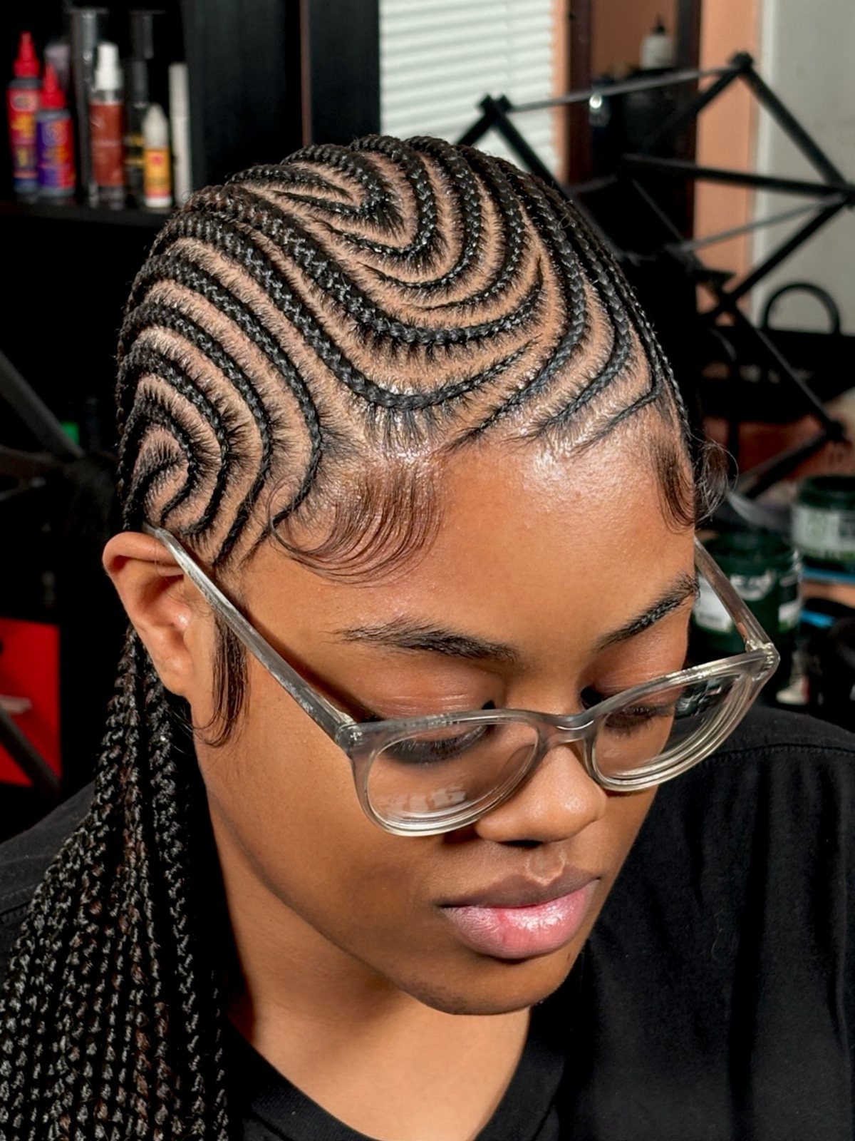 Woman with dark hair styled in precise zigzag stitch braids attached to the scalp.
