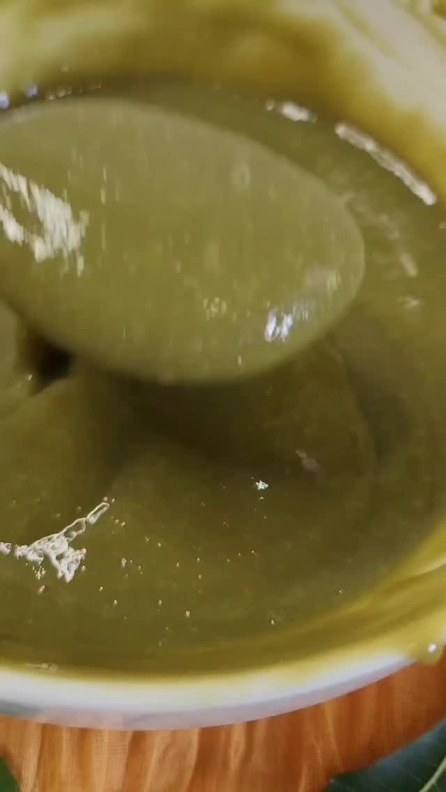 Green paste in a bowl being scooped up with a metal spoon