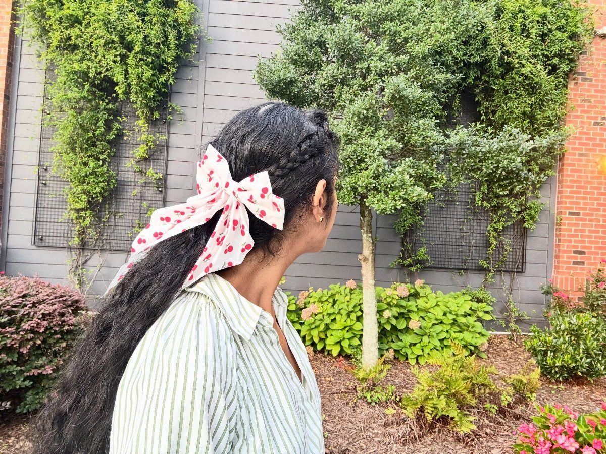 Woman with long dark hair featuring a partial braid and red heart bow.