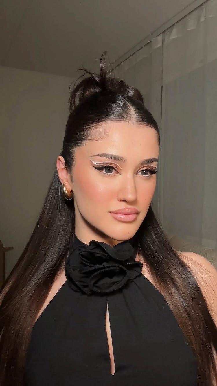 Woman with dark hair in a half-up top knot and straight loose hair.