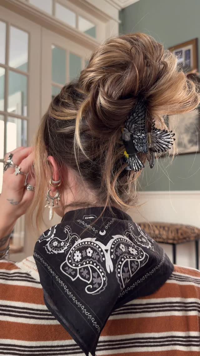 Blonde hair in a messy bun with a black bird hair clip and bandana.
