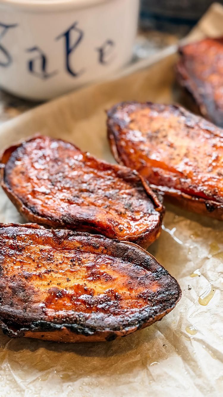 Roasted sweet potato slices with charred edges on brown parchment paper.