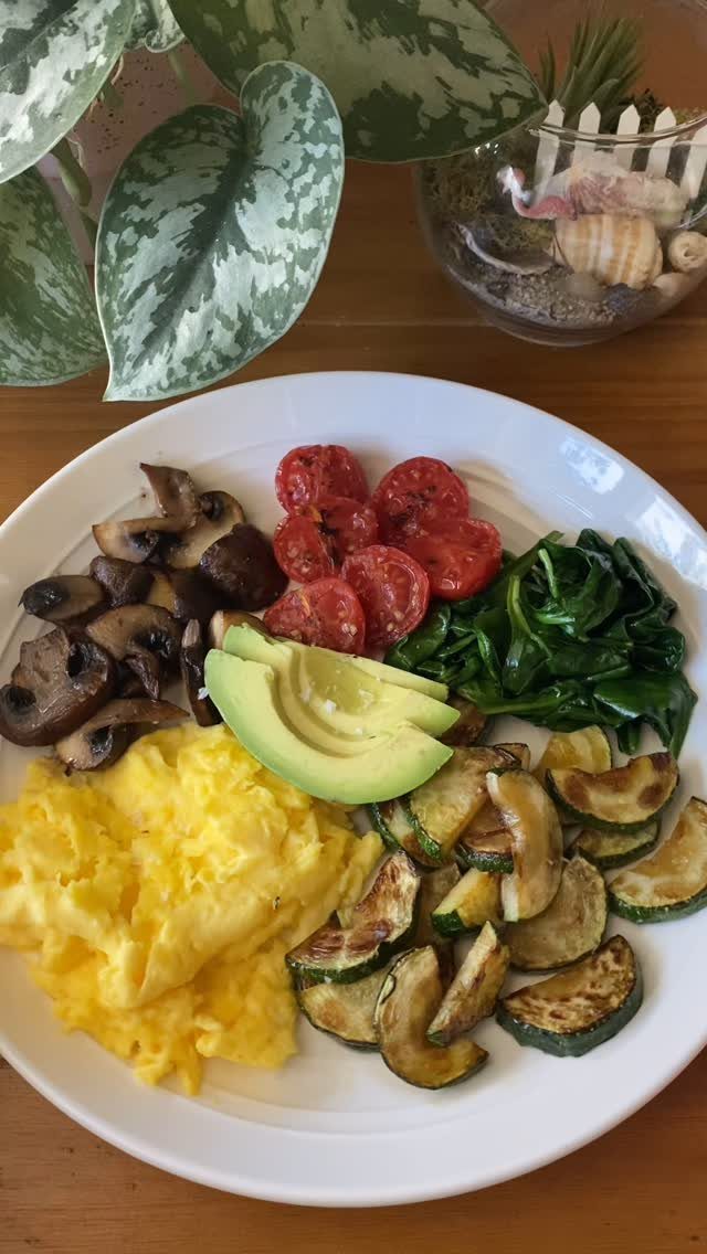 Healthy breakfast plate with eggs, avocado, spinach, mushrooms, tomatoes, and zucchini.