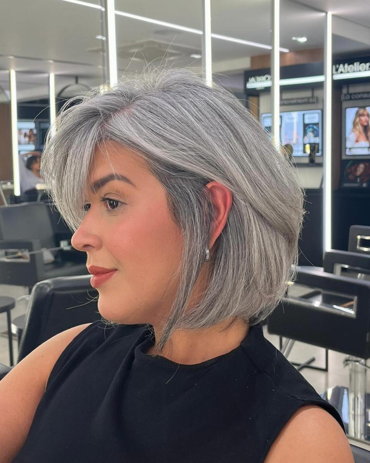 Woman with a short silver-gray bob haircut posing in a professional hair salon.