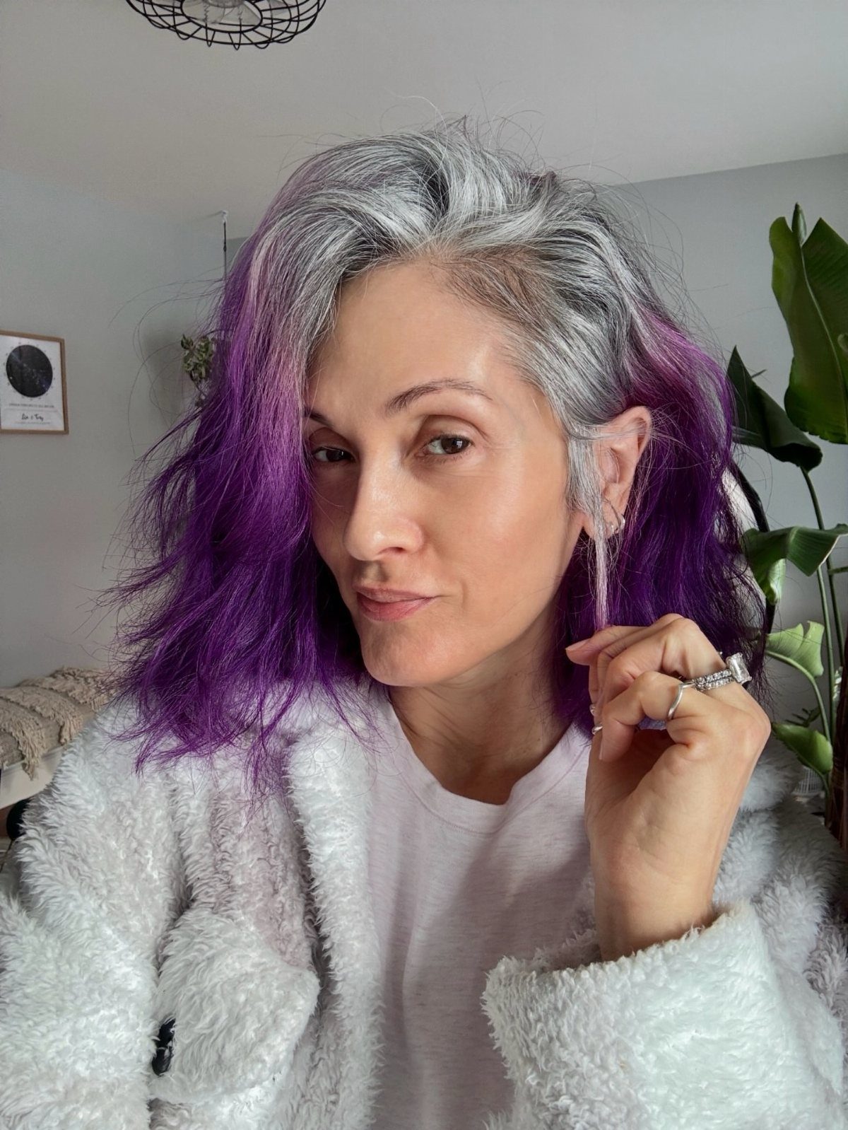 Woman with purple hair showing gray roots growing out at the crown.