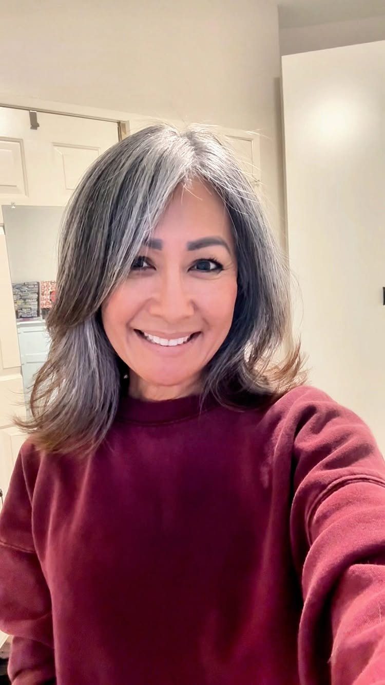 Woman with gray and brown hair smiling in a maroon sweatshirt.