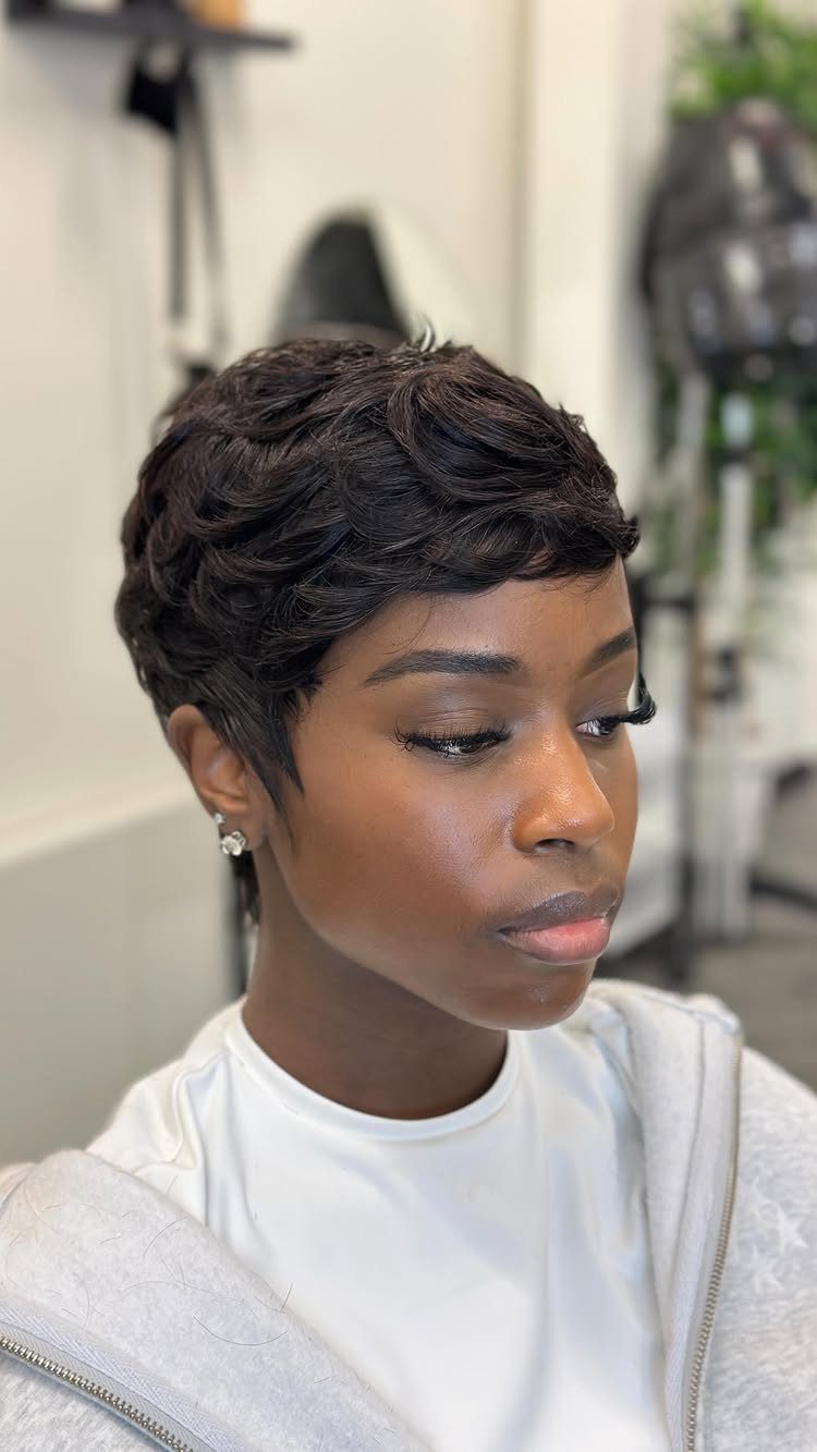 Woman with a tapered pixie cut featuring dark, textured layers on top.