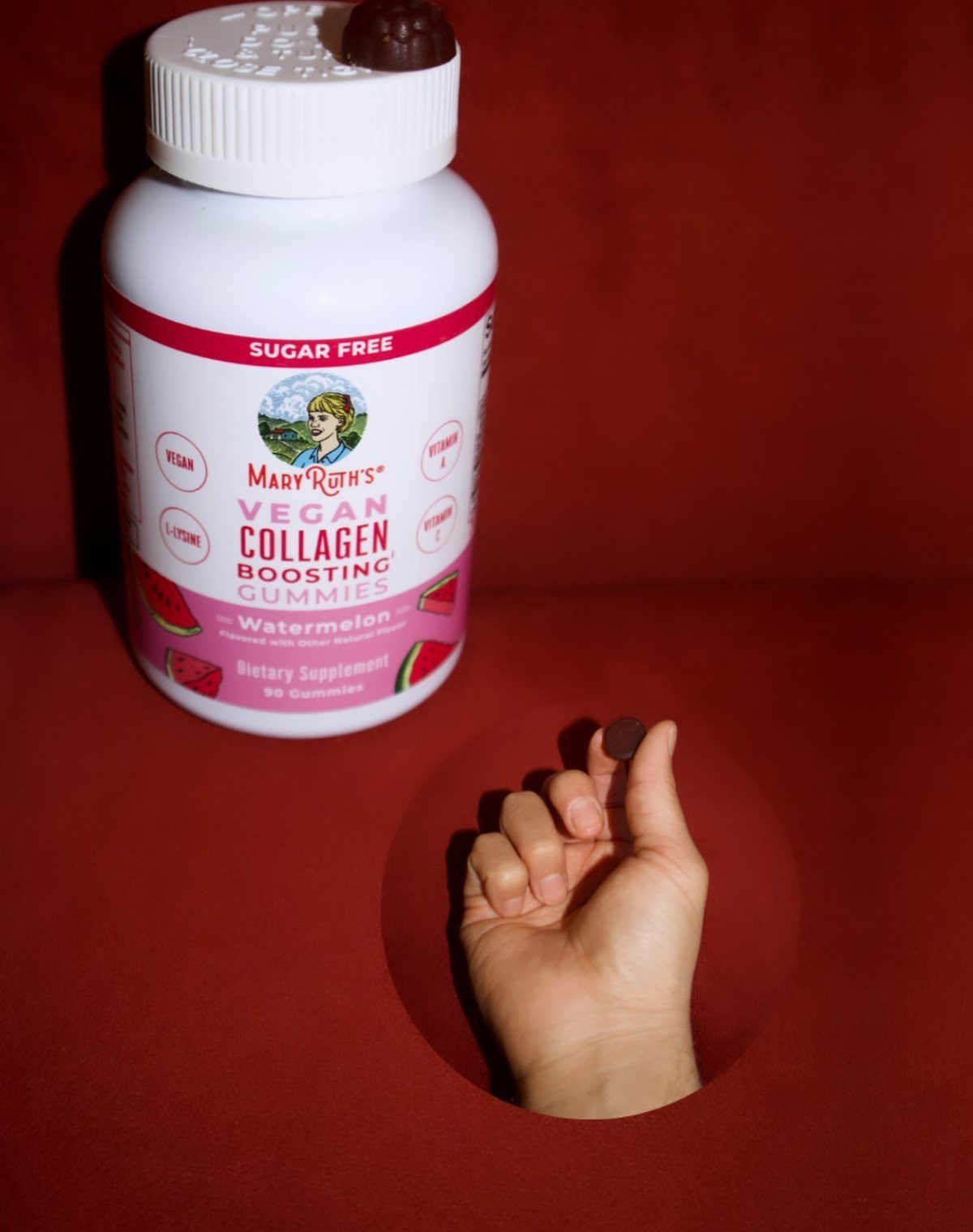 Mary Ruth's Vegan Collagen Boosting Gummies bottle with a hand holding one gummy.