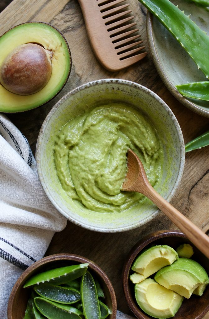 Ripe avocado with aloe gel and melted coconut oil in a bowl