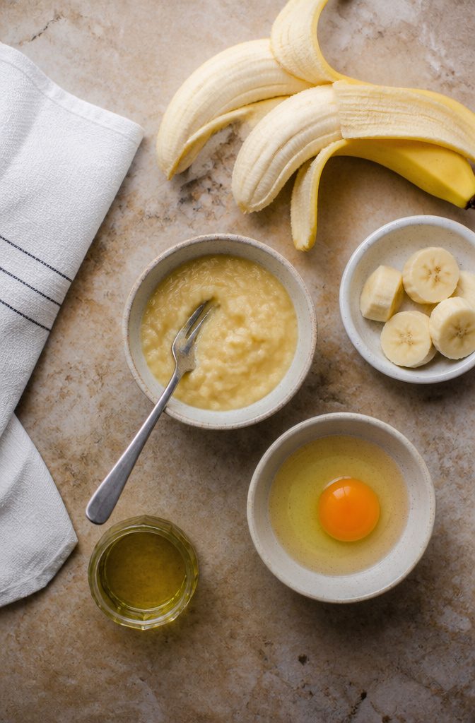 Eggs banana and coconut oil arranged beside a mixing bowl