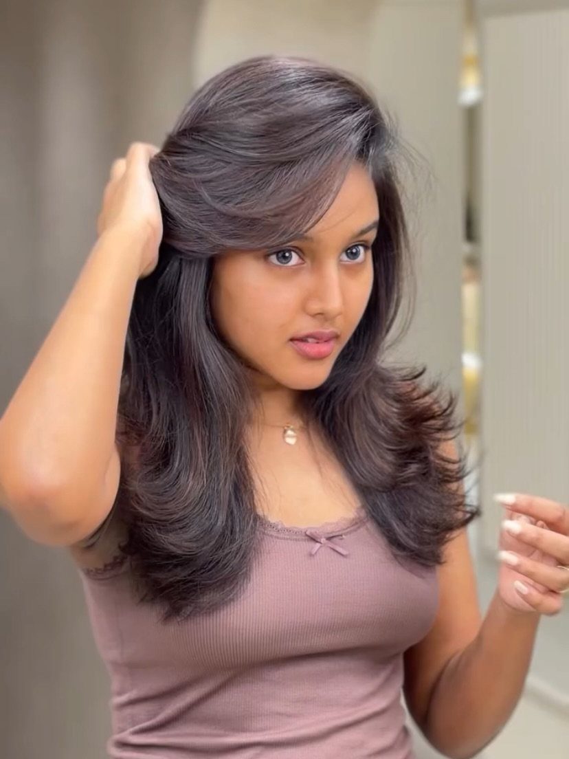 Woman with long dark brown hair and side-swept bangs in voluminous waves.