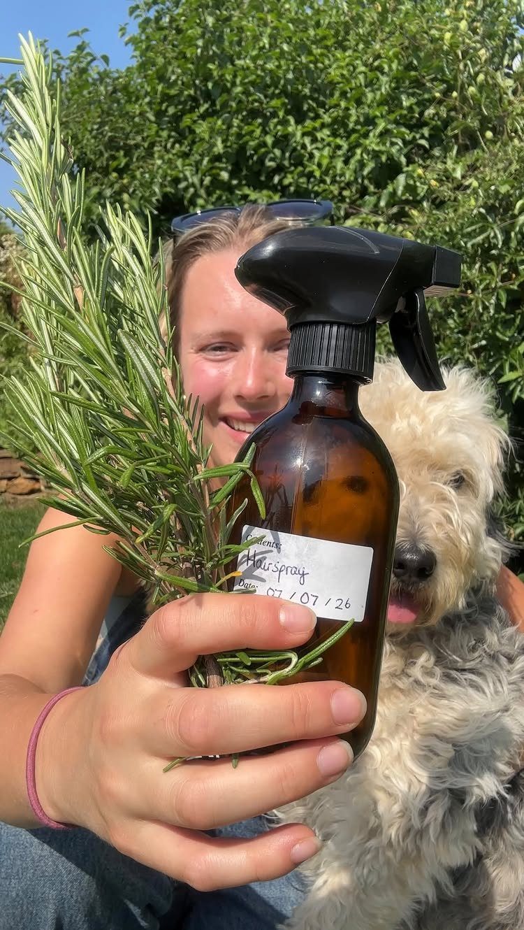 Woman holding a rosemary sprig and a brown spray bottle with a dog.