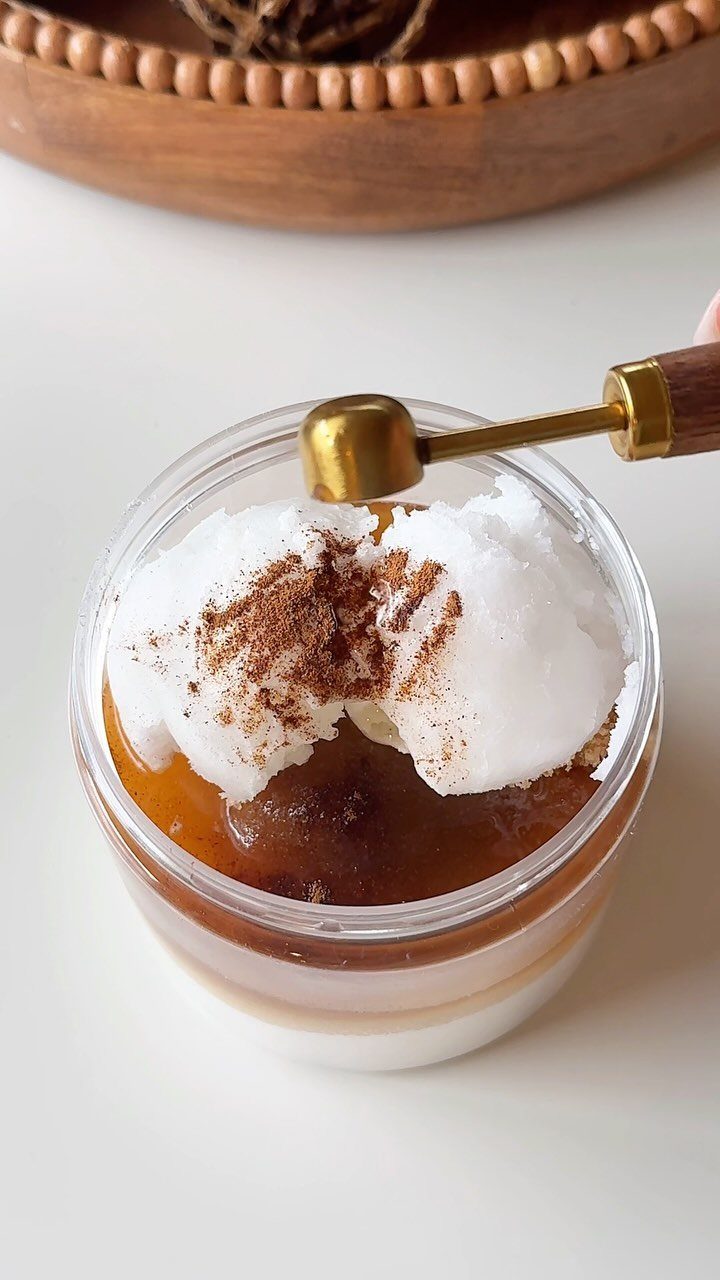 Cinnamon and brown sugar scrub in a glass jar with a gold spoon.