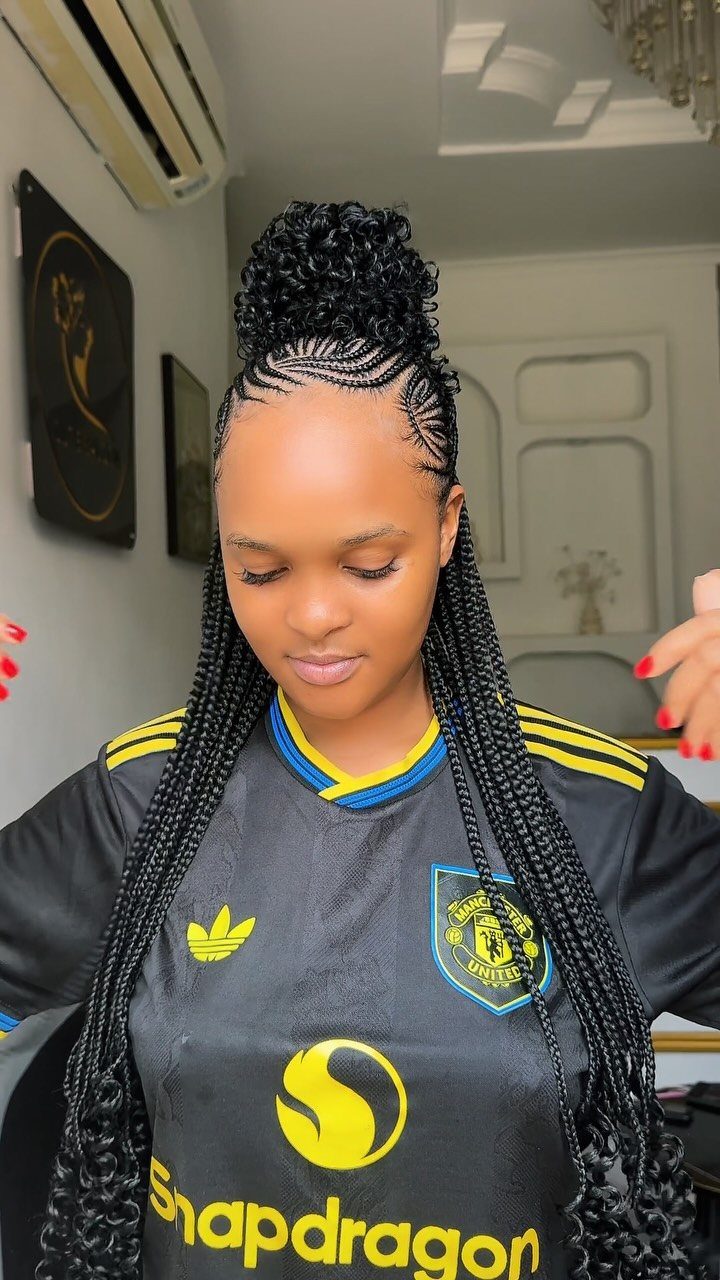 Woman with long thin braids and a curly high ponytail wearing a sports jersey.