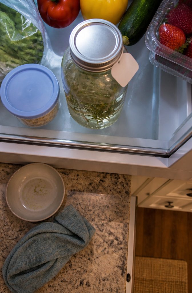 Jar of homemade rosemary water stored on a refrigerator shelf