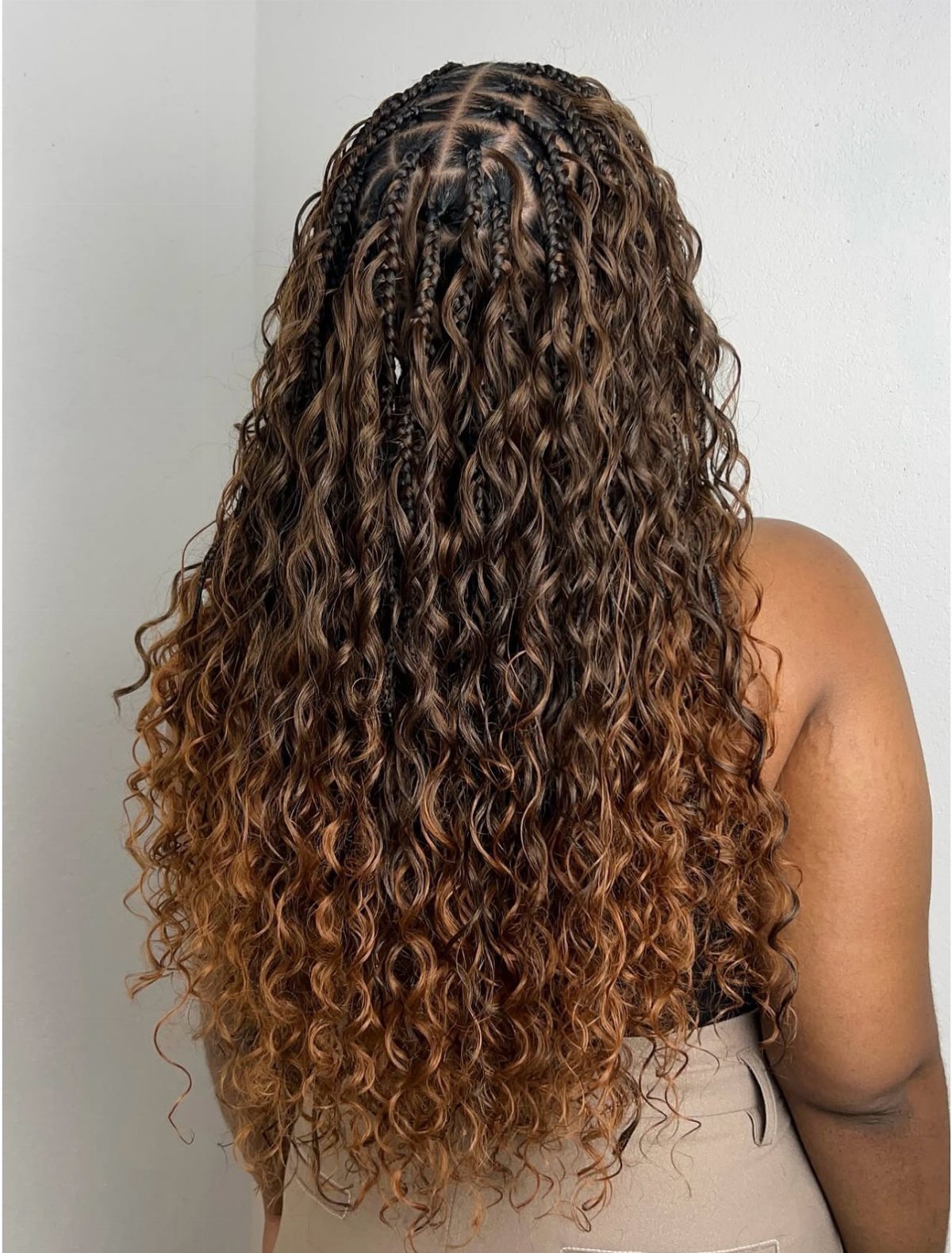Long curly brown hair with cornrow braids on the scalp and loose curls.
