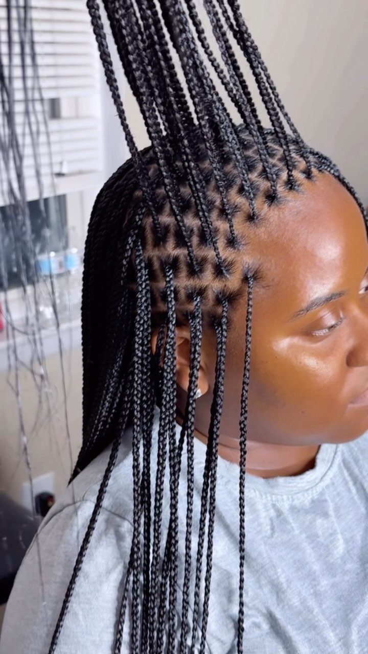 Woman with black box braids showing square scalp sections and long braided hair.
