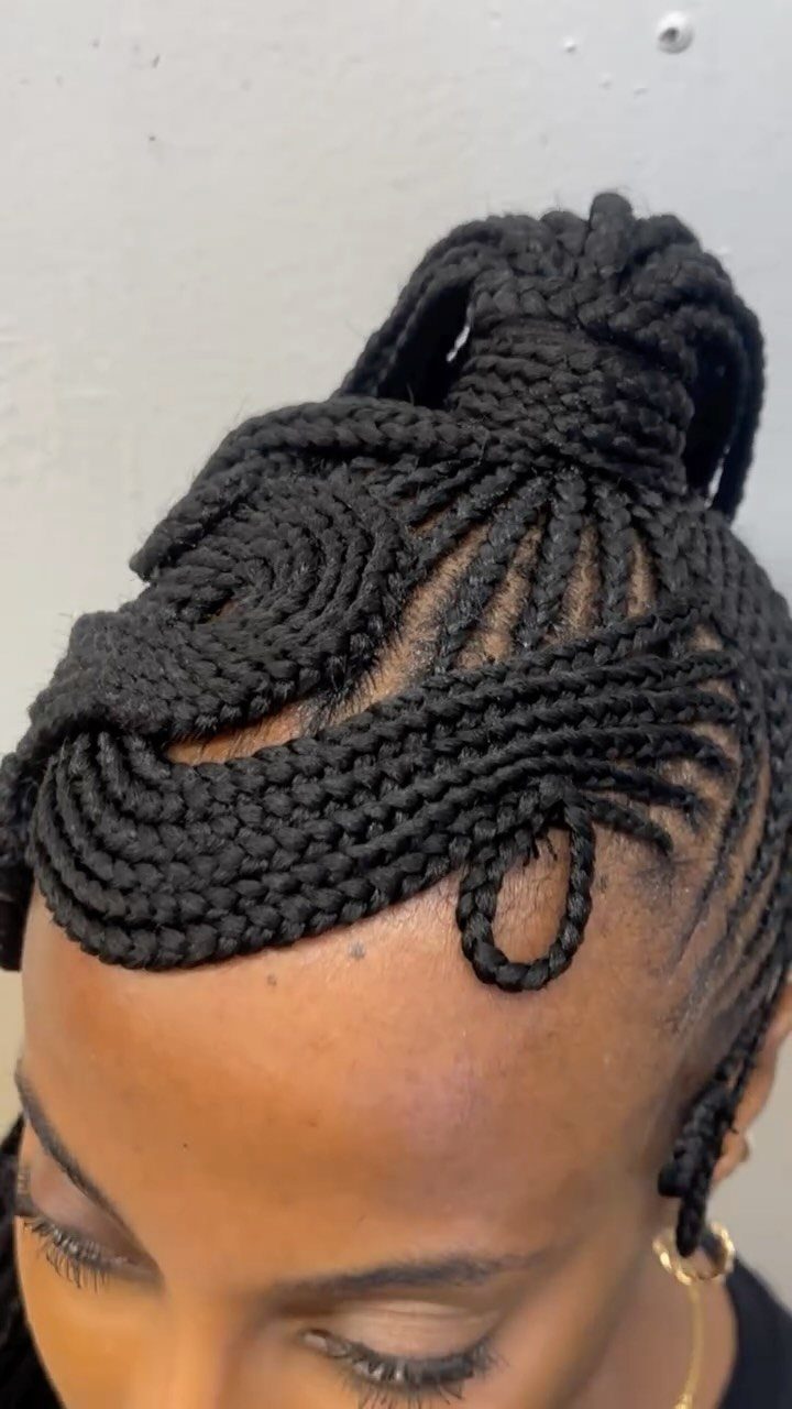 Intricate black cornrow braids gathered into a high bun on a person's head.