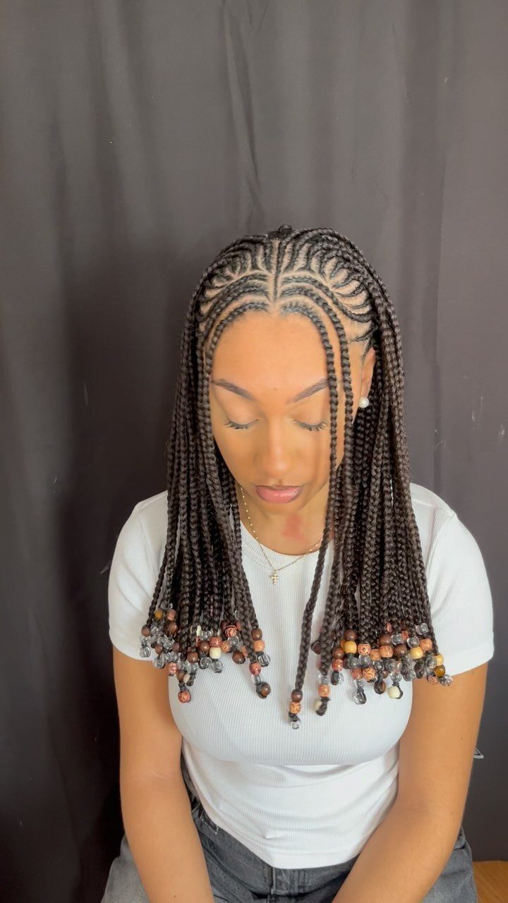 Woman with cornrow braids featuring decorative brown and gold beads at the ends.