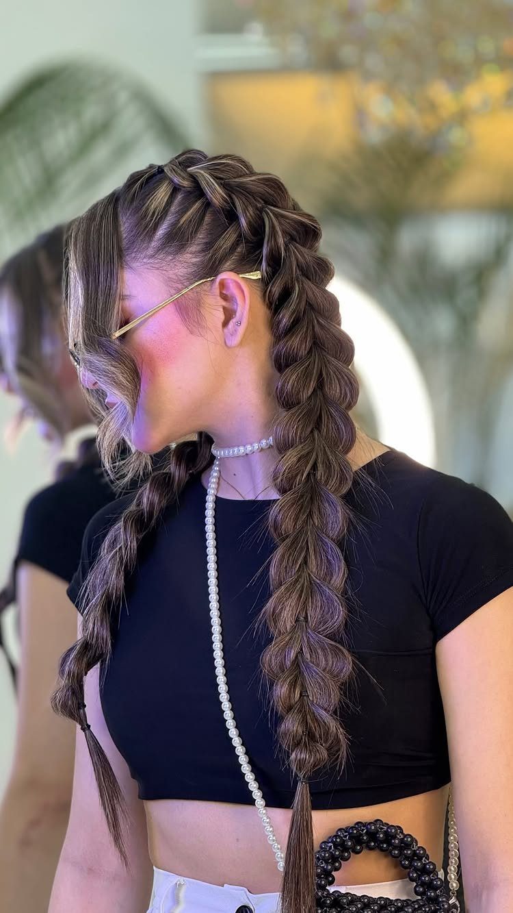 Woman with brown hair styled in two thick, raised Dutch braids and pearl necklace.