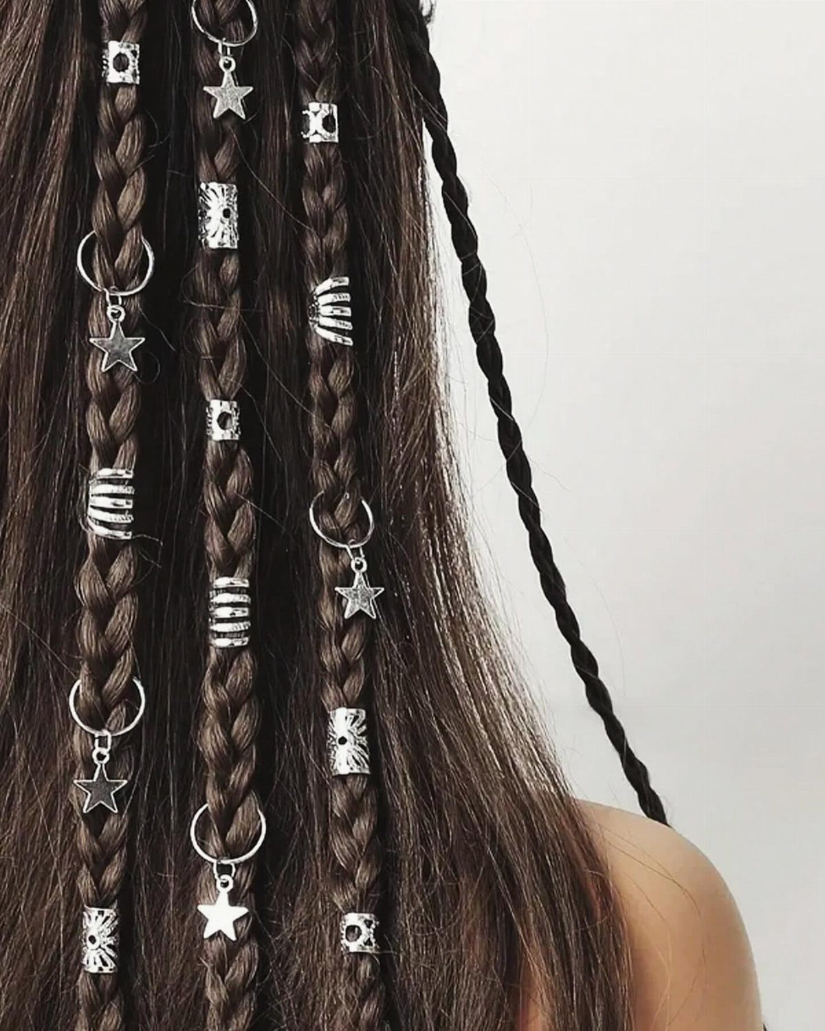 Brown braids decorated with silver star charms and metallic hair cuffs.