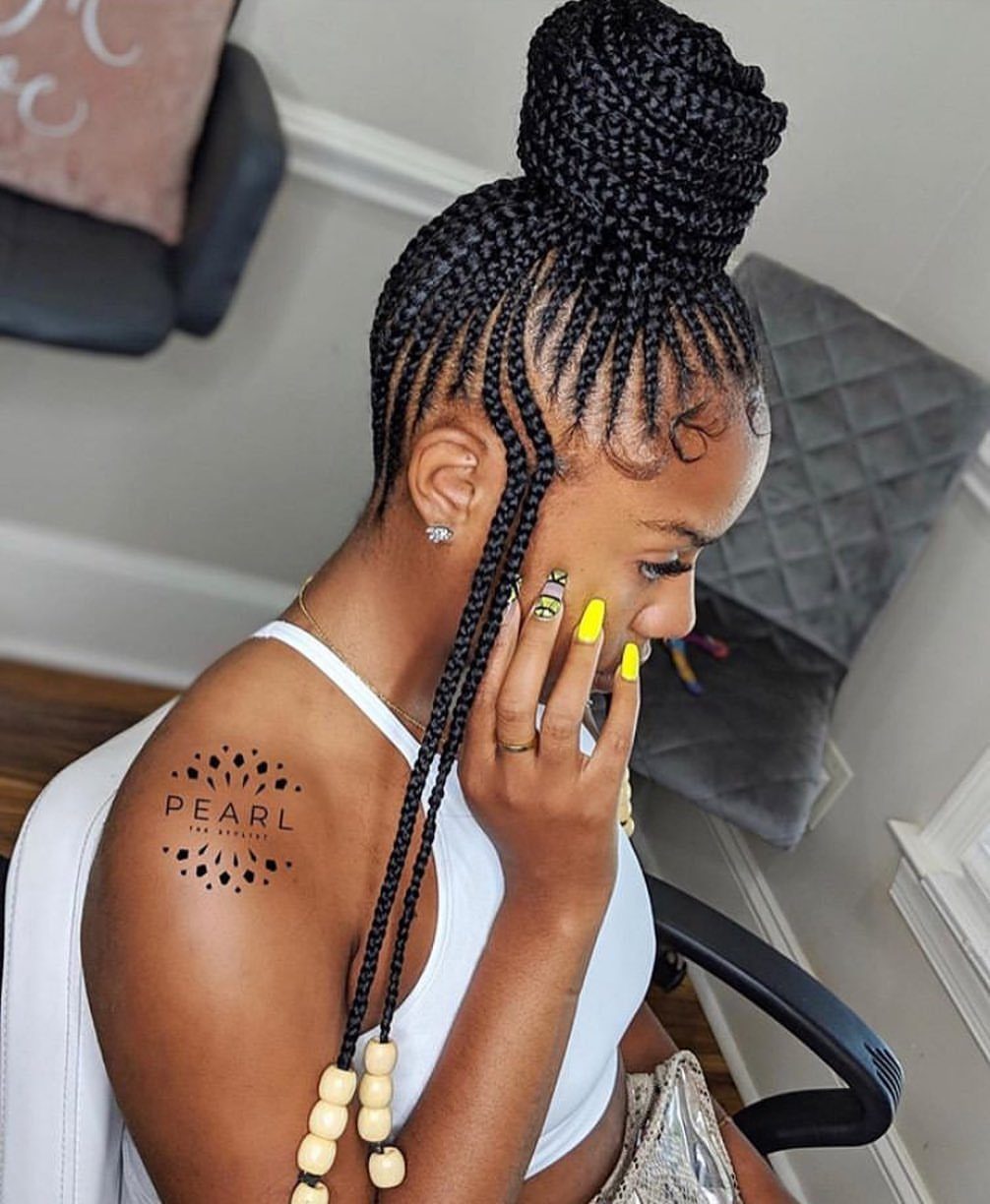 Woman with black scalp braids gathered into a high, voluminous braided bun.