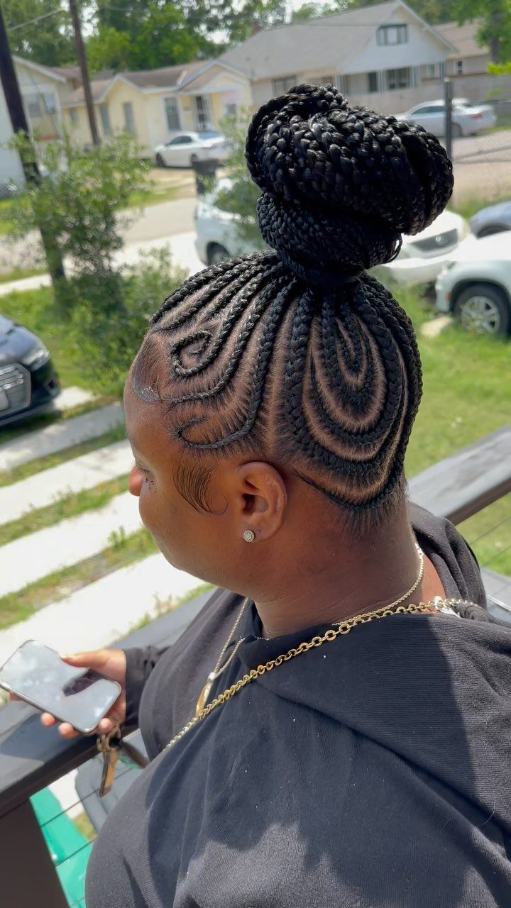 Curved cornrow braids gathered into a large braided bun on a person's head.