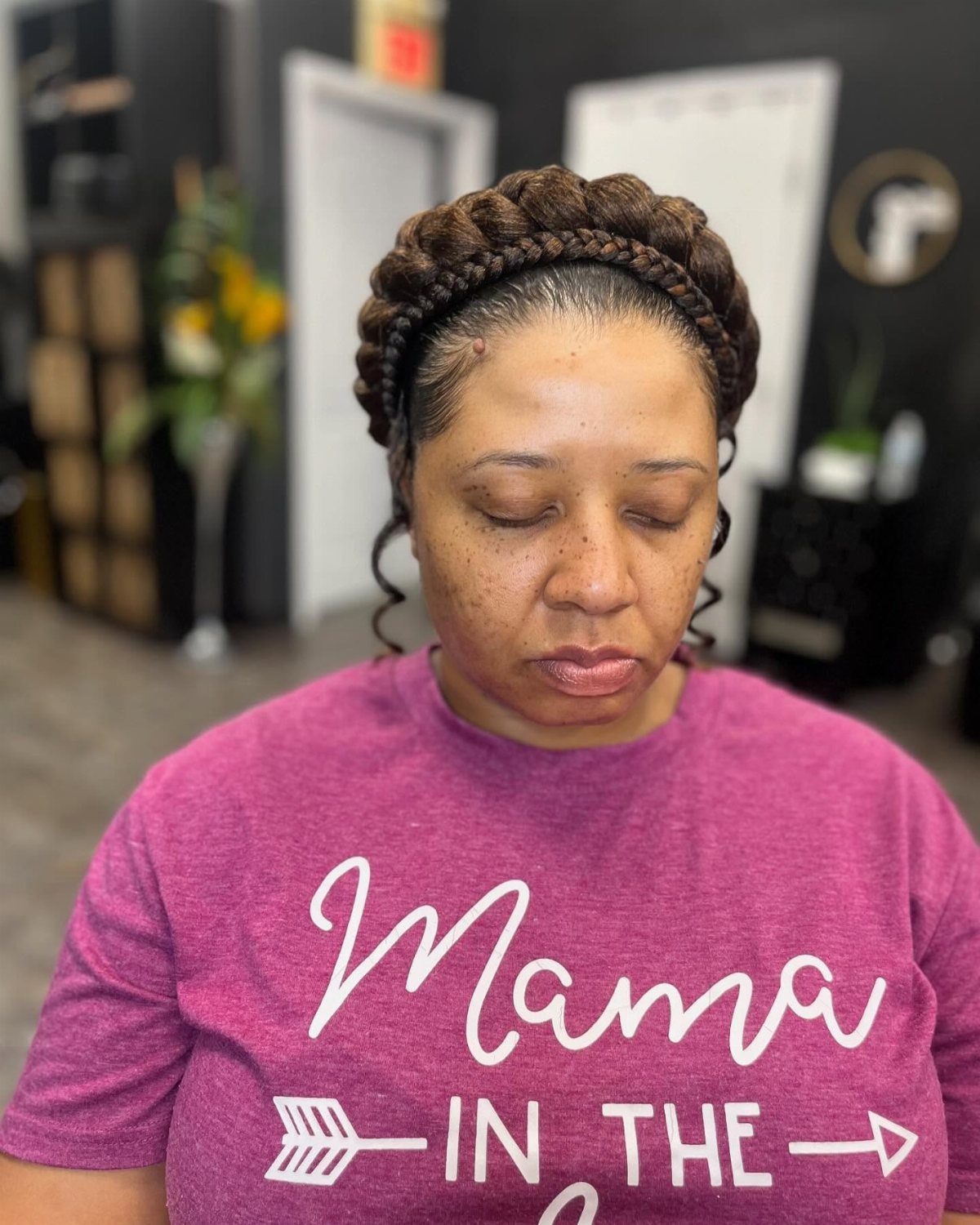 Woman with a thick braided halo crown hairstyle wearing a magenta t-shirt.
