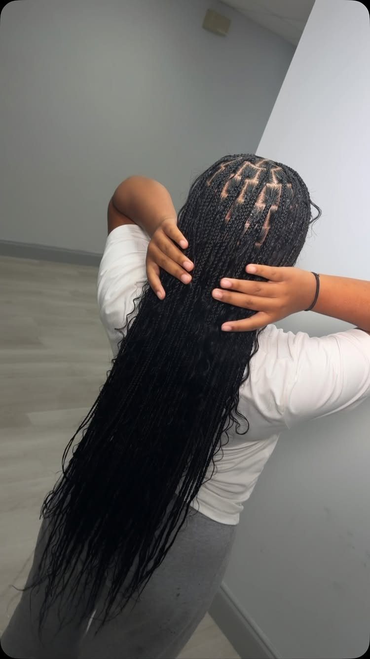Long black knotless braids with neat rectangular parts on a person's scalp.