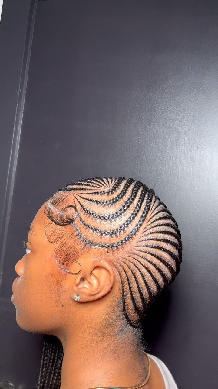 Side profile of a person with curved, side-swept cornrow braids on their scalp.