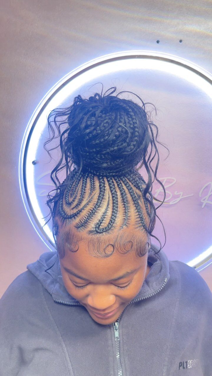 Woman with stitch braids on her scalp gathered into a high braided bun.