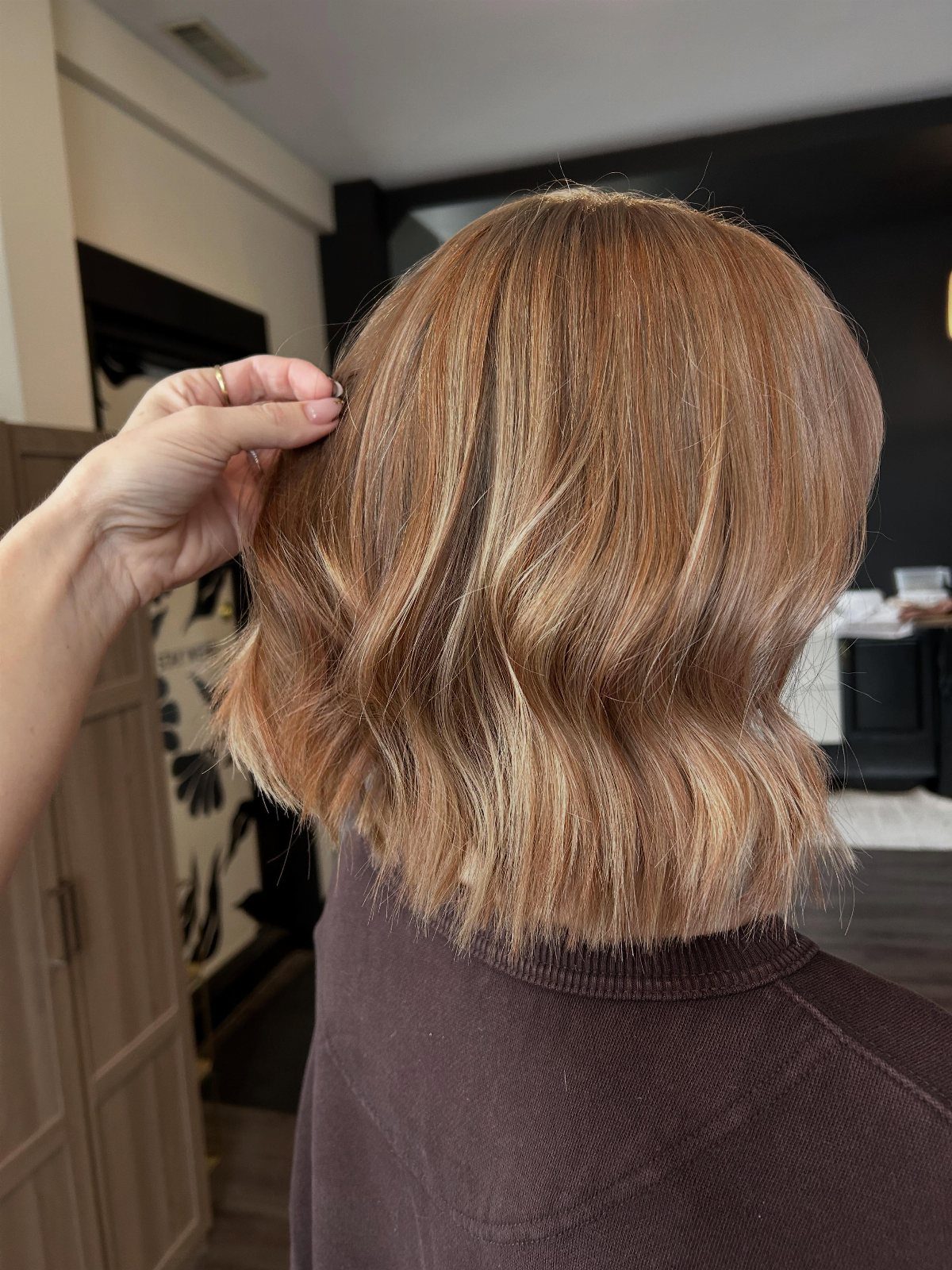 Short wavy light brown bob haircut on a person seen from behind.