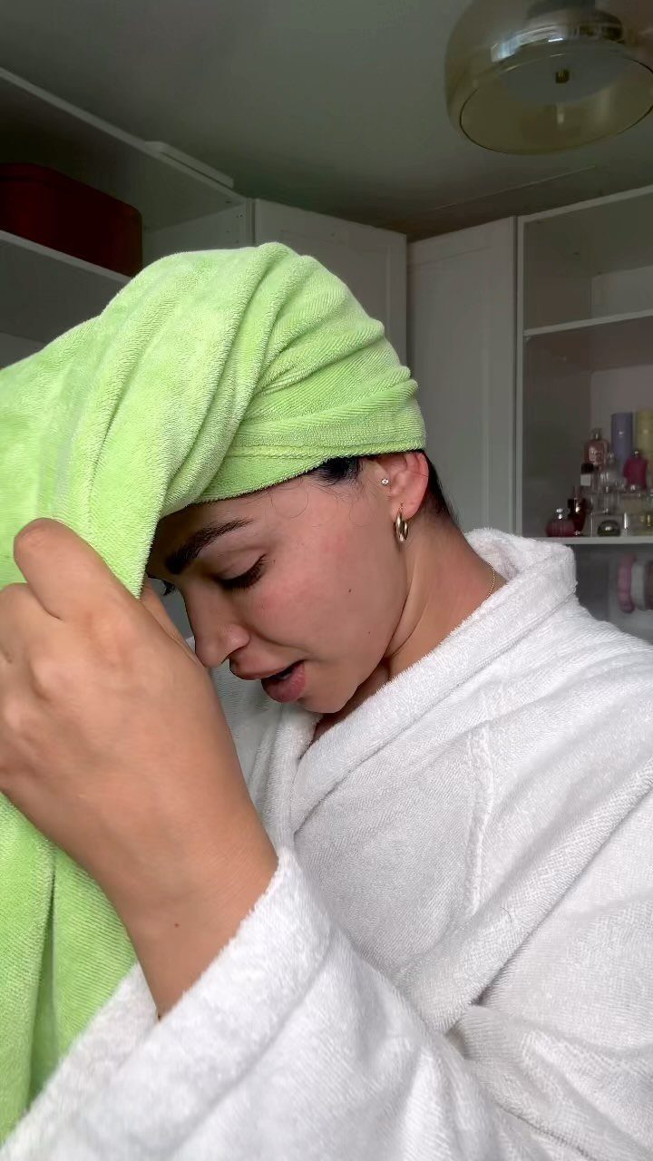 Woman in a white bathrobe with a lime green towel wrapped around her head.