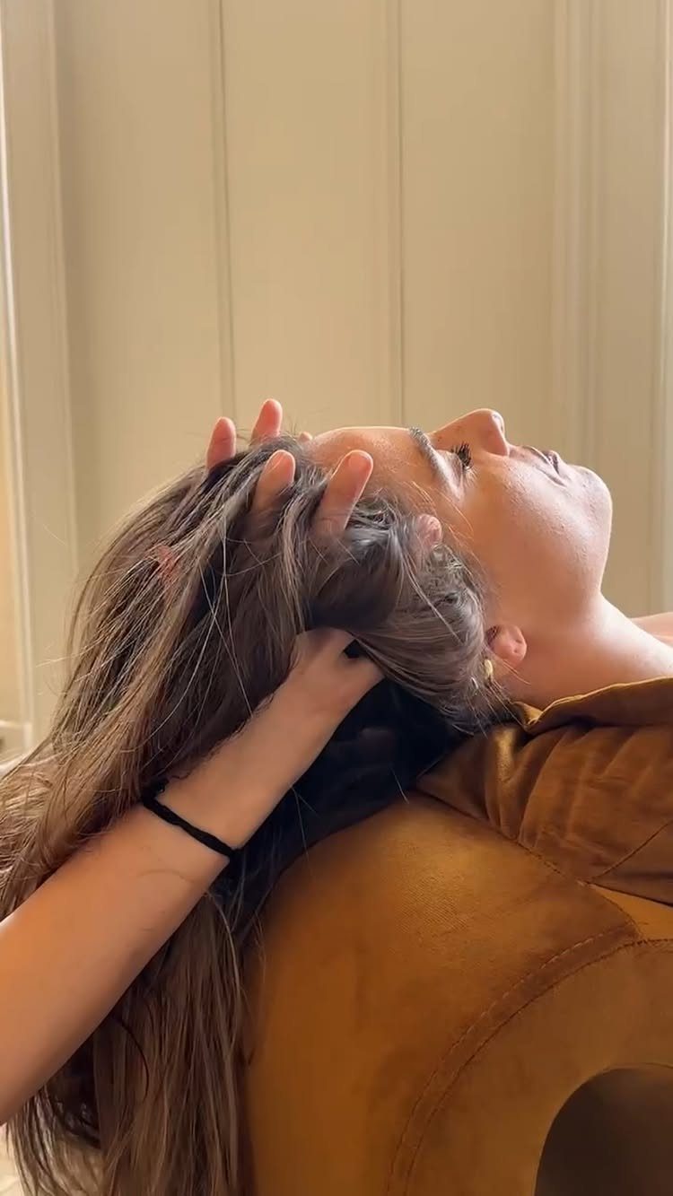 Person receiving a scalp massage with hands massaging the head and hair.