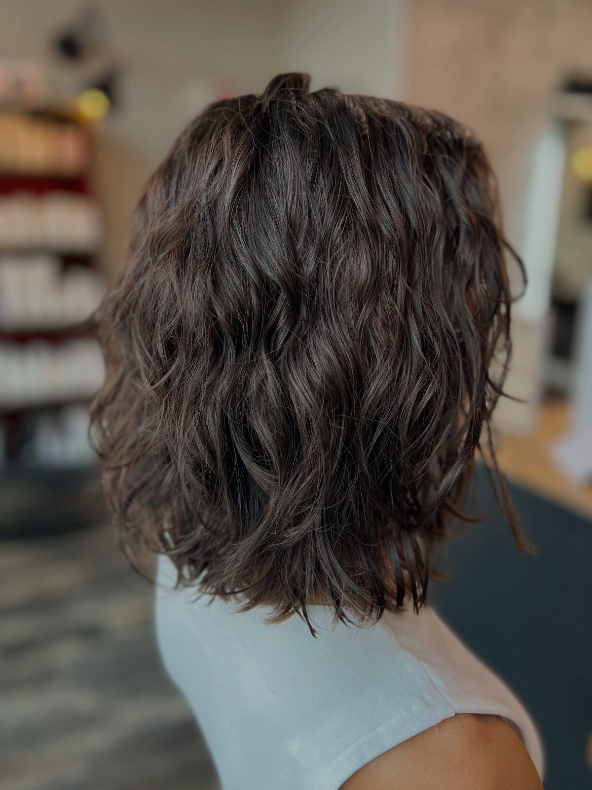 Shoulder-length wavy dark brown hair with volume and texture seen from behind.