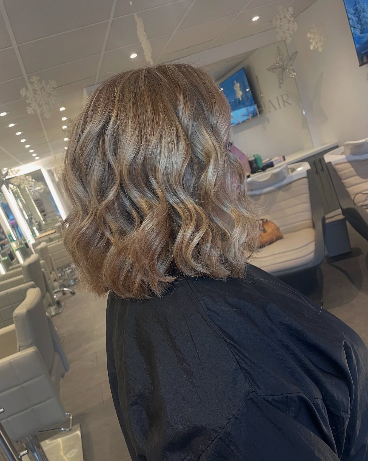 Shoulder-length wavy light brown hair with blonde highlights in a hair salon setting.