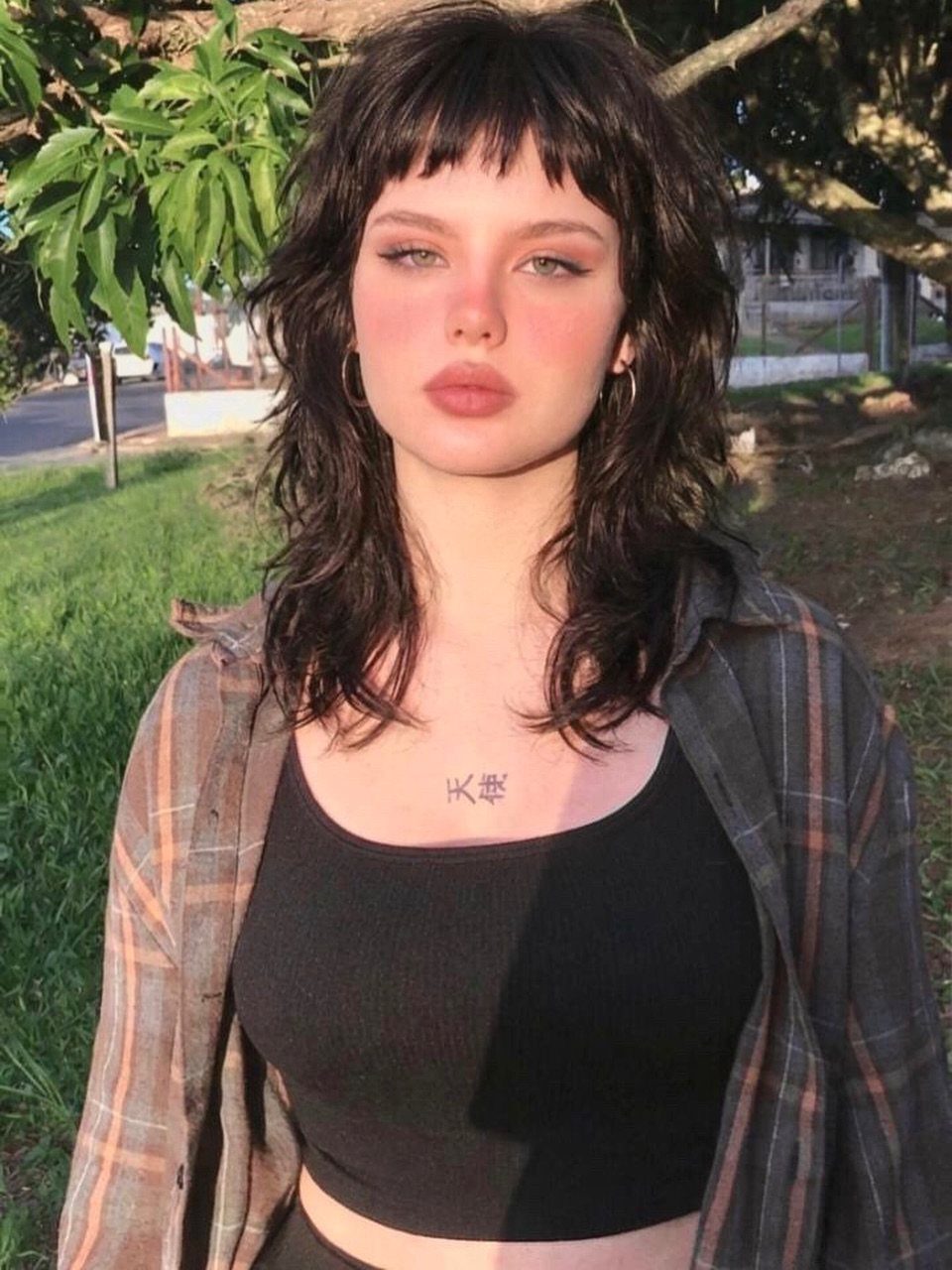 Woman with a wavy mullet haircut featuring short bangs and shaggy layers.